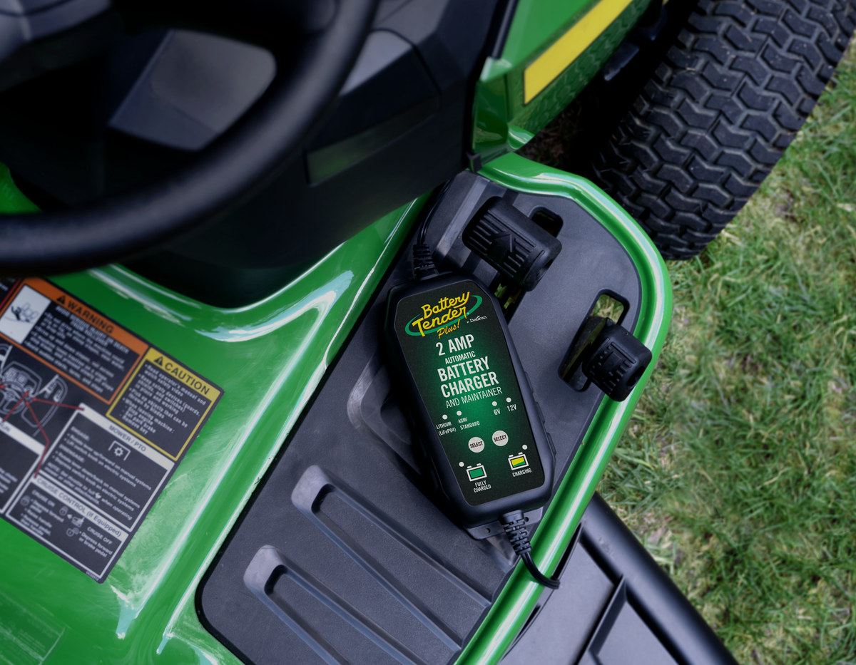 Battery Tender® charger connected to a lawn mower battery in a garage, ready for all-season maintenance.