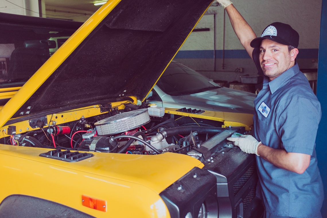 Mechanic testing a car battery not holding charge, with a Battery Tender charger connected in the garage